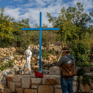 Pilgrim praying at the Blue Cross in Medjugorje
