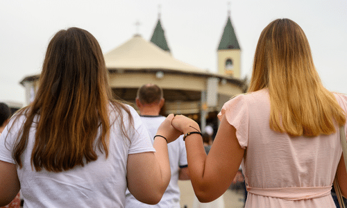 Pilgrims holding hands during Mass at St. James Church in Medjugorje