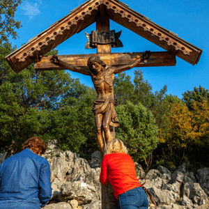 Pilgrims praying before a crucifix on Apparition Hill in Medjugorje