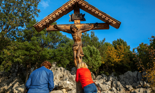 Pilgrims praying before a crucifix on Apparition Hill in Medjugorje